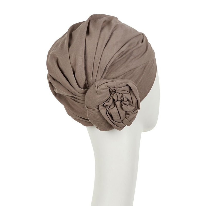 Baksidan av en kamelfärgad Zuri turban i mjuk bomull, med en blomdetalj synlig på sidan