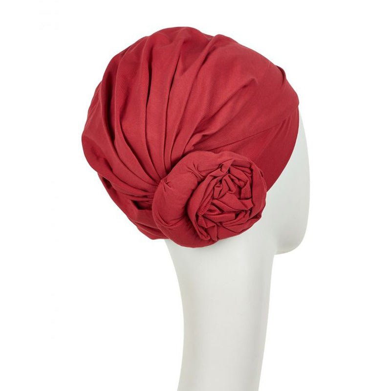 Baksidan av en röd Zuri turban i mjuk bomull, med en tydlig blomdetalj på sidan
