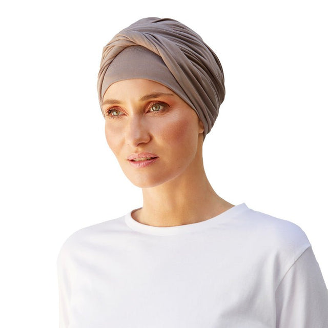 Kvinna med en bekväm brun Shakti turban i bambuviskos, med det breda bandet vridet fram