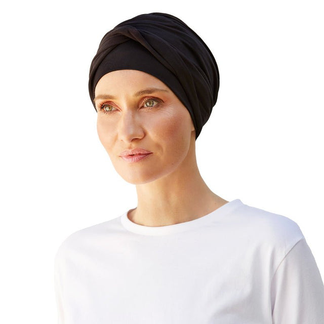 Kvinna bär en klassisk svart Shakti turban i bambuviskos, med det vridna pannbandet fram