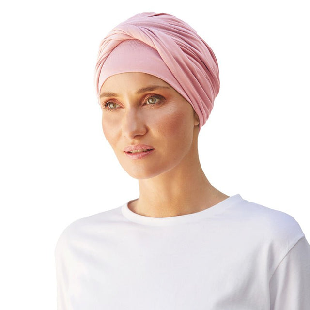 Kvinna bär en elegant rosa Shakti turban i mjuk bambuviskos, vriden framtill för volym