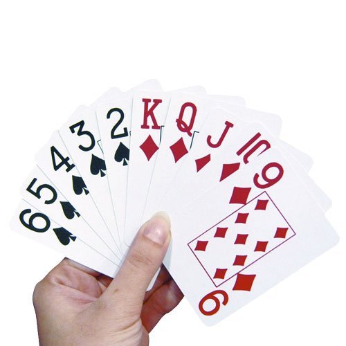 En hand håller upp en kortlek med stora siffror och symboler, tydligt synliga för enklare spel