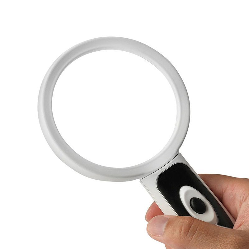 En hand håller i det vita och svarta förstoringsglaset med LED-ljus