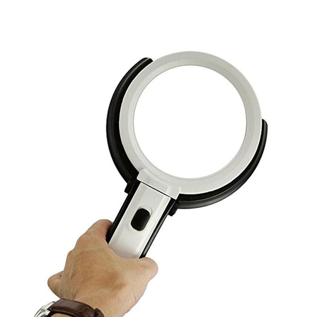 En hand håller den vita och svarta luppen som ett handhållet förstoringsglas