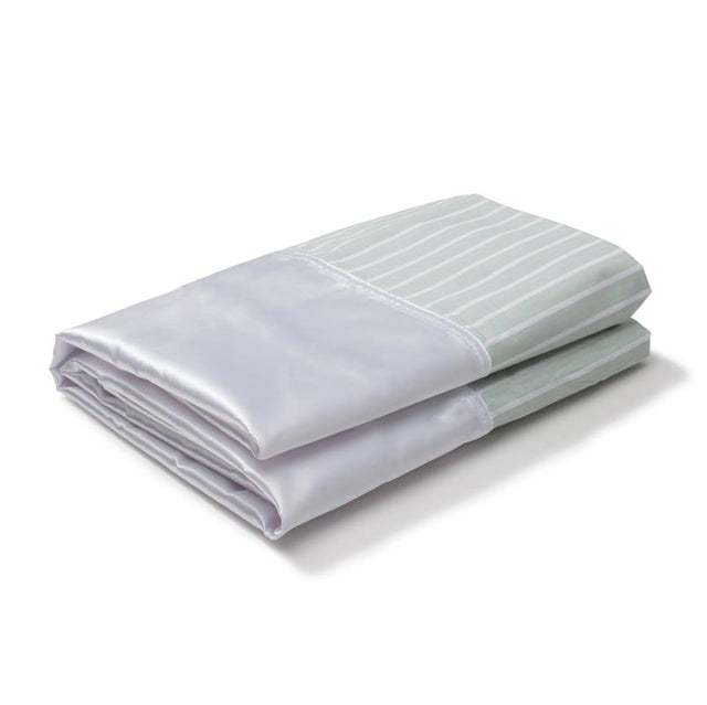 Ett hopvikt SatinSheet glidlakan i vitt satin och grönrandigt tyg, sett snett framifrån