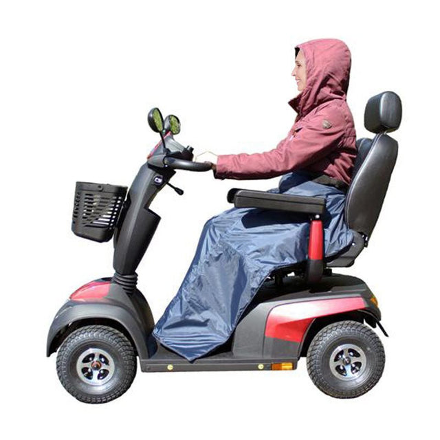 Kvinna sitter på en permobil med ett mörkblått fodrat regnöverdrag som täcker ben och underkropp