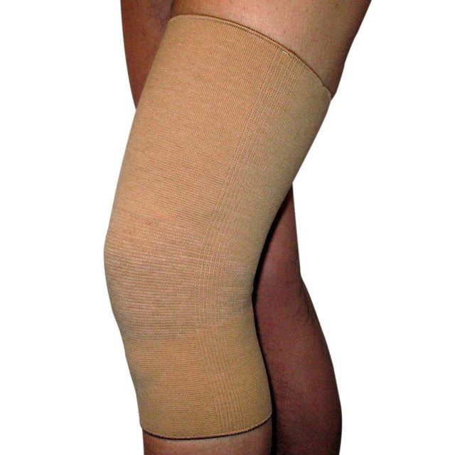 Beige elastiskt knäskydd med ull, buret på ett ben och sett från sidan