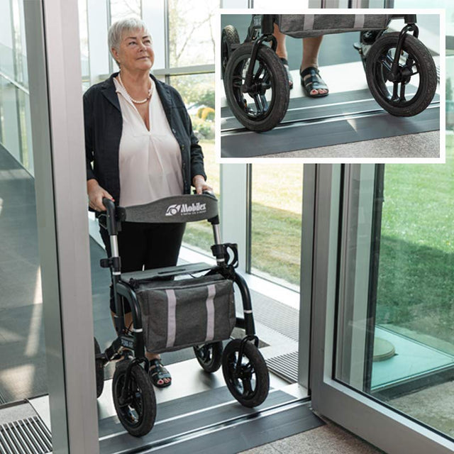 Senior kvinna använder en grå gummiramp med sin rollator för att passera en dörröppning