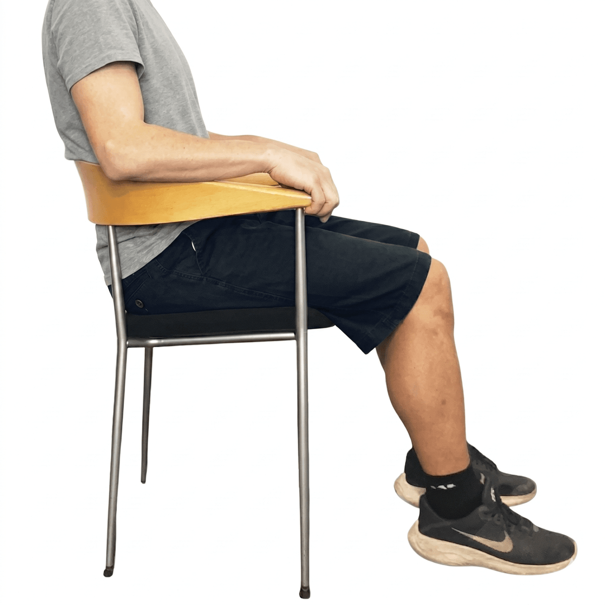 En person sitter bekvämt i mörkblå shorts med elastisk midja på en stol, visar passformen