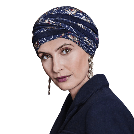 Kvinna bär en Shanti turban i Amber Garden-mönster med röda och gyllene nyanser på mörkblå botten