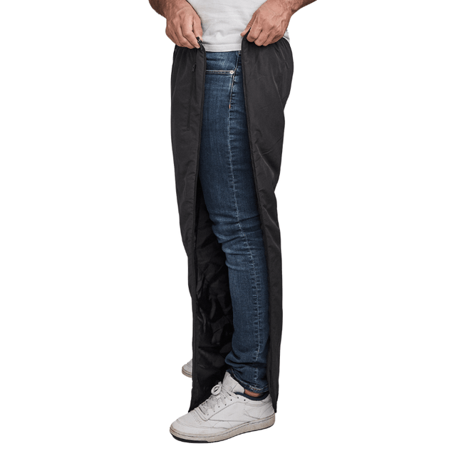 Svarta Dobsom termobyxor med hel dragkedja längs sidan, delvis öppen över jeans och vita skor