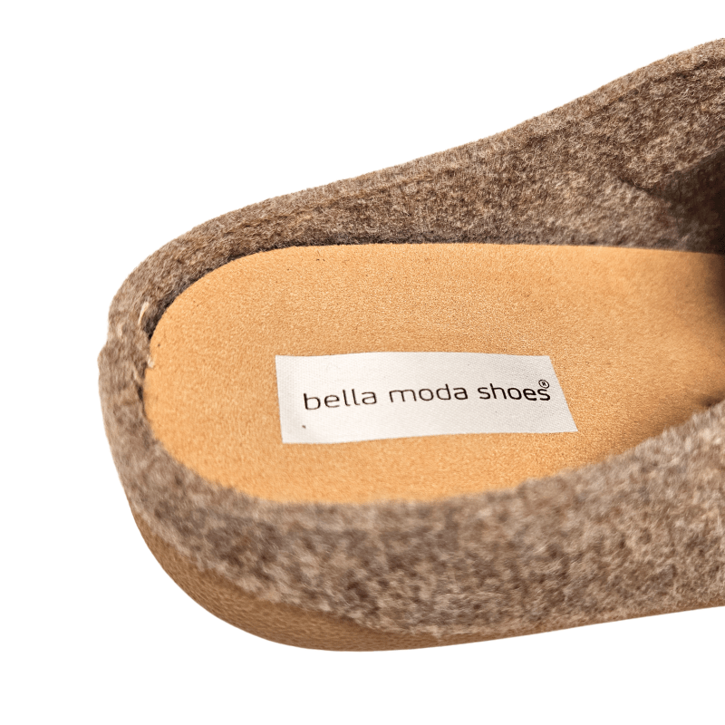 Närbild på den beige ulltofflans innersula med texten "bella moda shoes" tryckt på en etikett