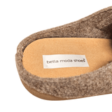 Närbild på den beige ulltofflans innersula med texten "bella moda shoes" tryckt på en etikett