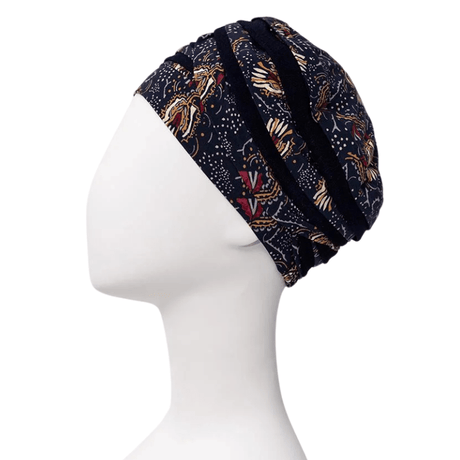 Shanti turban i Amber Garden-mönster med fjäder- och stammotiv på en vit skyltdocka, sedd från sidan